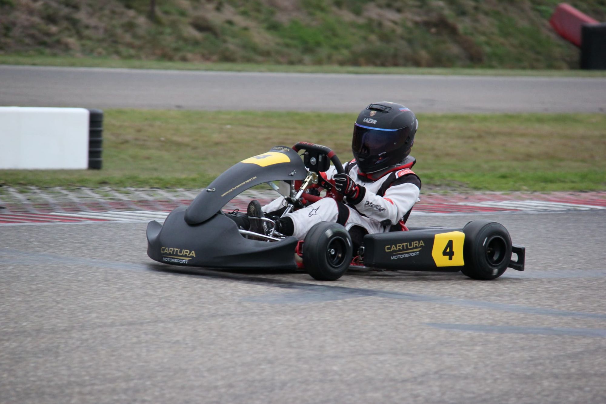 Kart in Cartura-livrei met nummer 4 in een bocht op het circuit